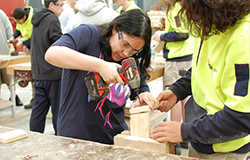 Young boy learning woodwork by his teacher
