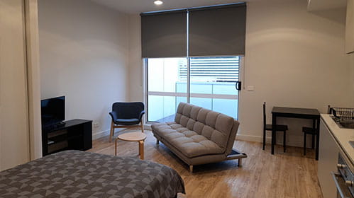 A bedroom featuring a bed, sofa, tv and desk set up