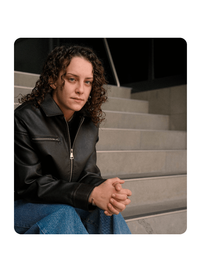 A young women sits outside on a concrete staircase
