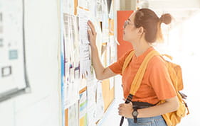 Female student reading the notice board