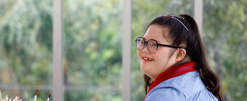 Teenage girl with long black hair and glasses smiling