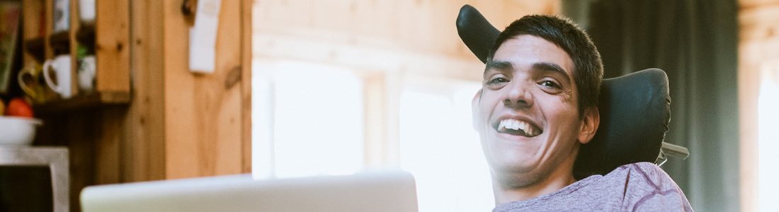 Young man in a wheelchair looking at his computer