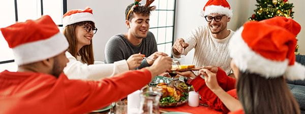 A group of five adults eating a meal around a table at Christmas