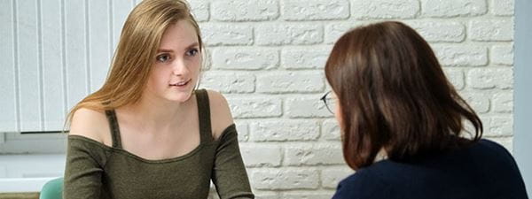 A lady speaking directly to a female teenager