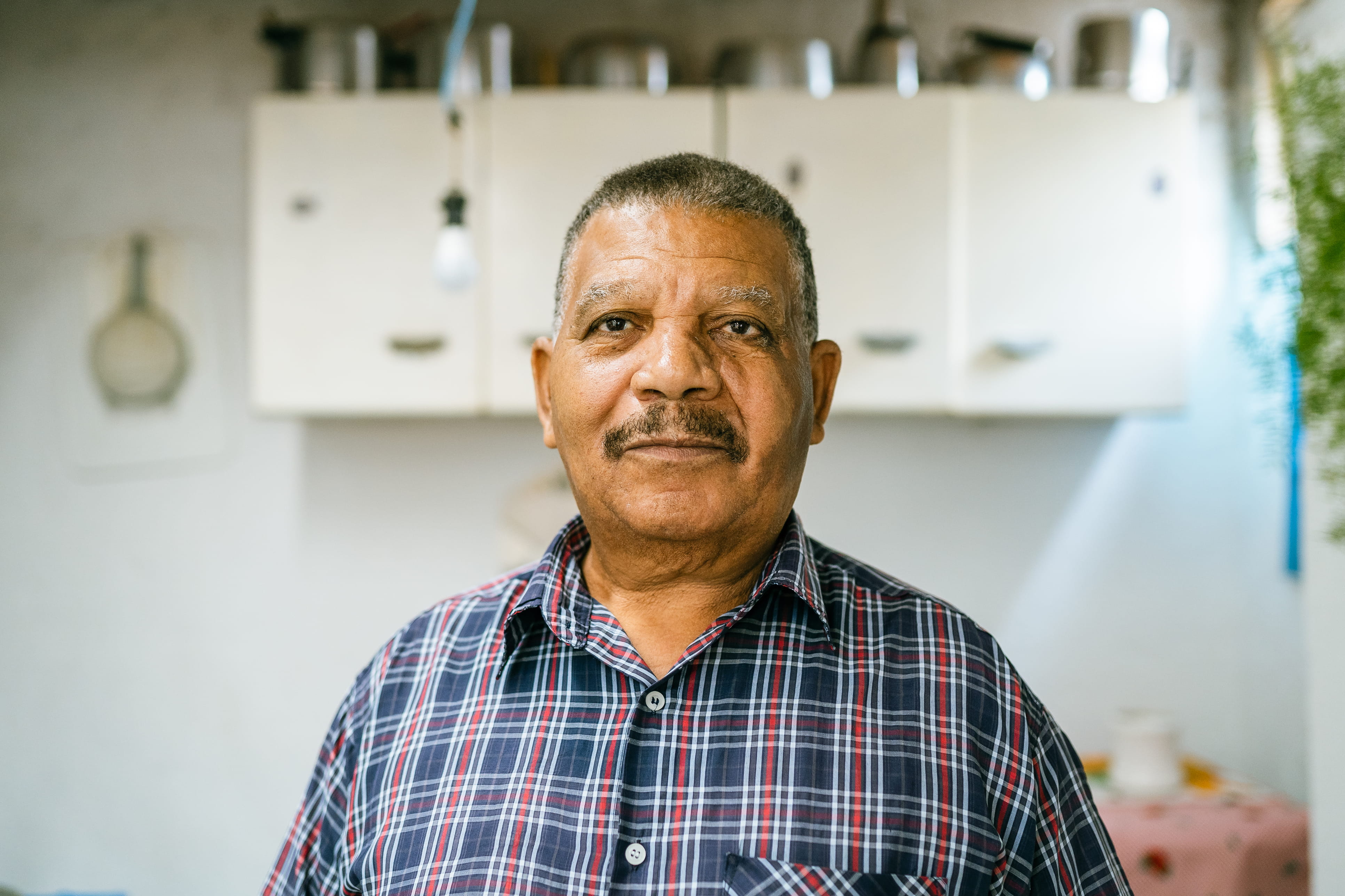 Older man standing in a kitchen.