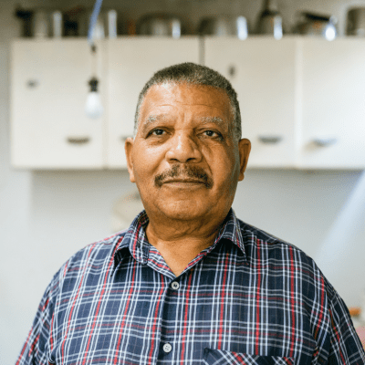 Older man standing in a kitchen.