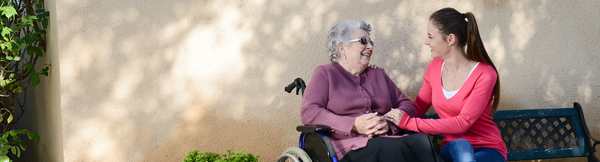 An elderly woman sitting outside with a palliative care worker.