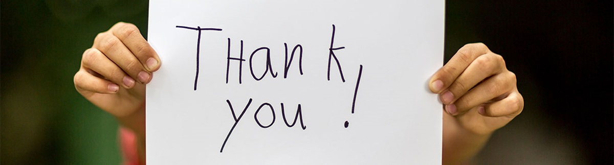 A thank you sign being held up by an unseen person.