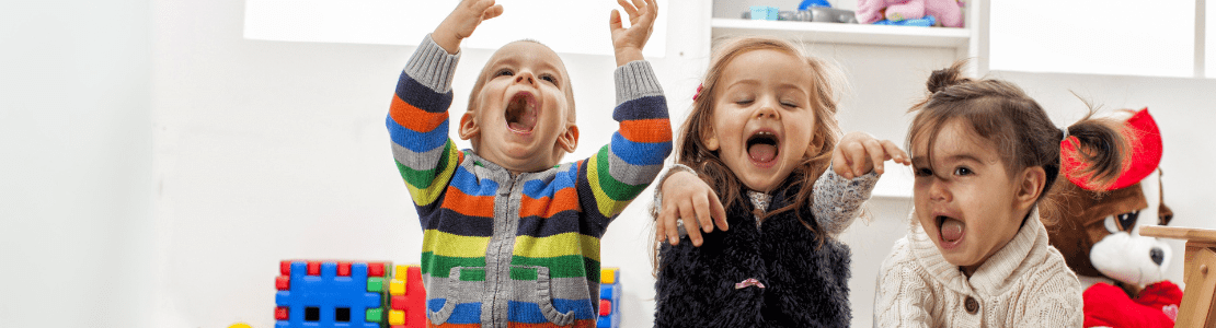 3 toddlers sitting on the floor of a playroom