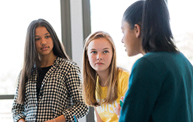 Three female teenagers talking to each other