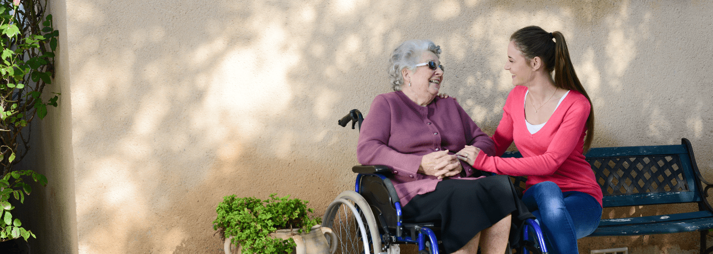 older lady in wheelchair talking to younger woman on a bench