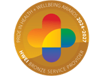 Bronze circular badge with a rounded rainbow-colored cross in the center. Text around the edge reads 'Pride in Health + Wellbeing Awards 2024-2027' and 'HWEI Bronze Service Provider