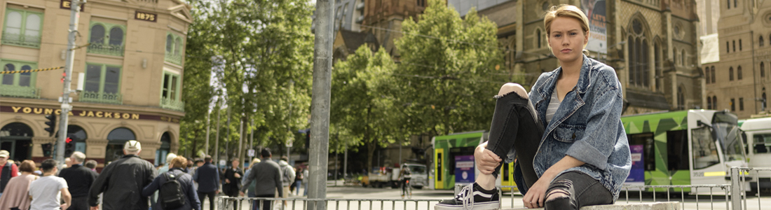 Photo of a young woman sitting outside in Melbourne's CBD