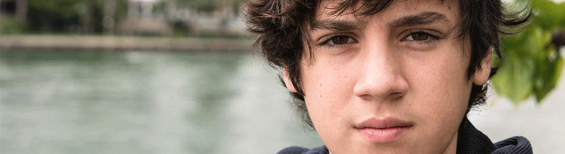 A teenage boy with black hair looking at the camera