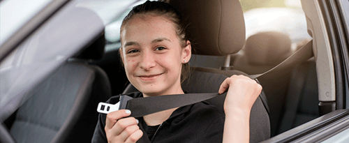 Young girl puts on her seat belt