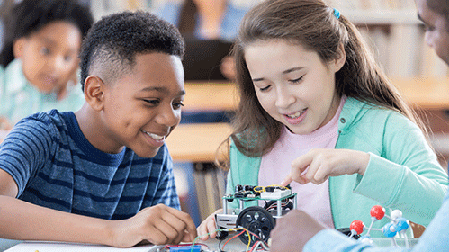 A young boy and girl doing science with a teacher