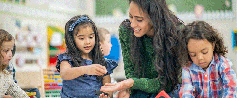 Group of children playing with an Educator on the floor