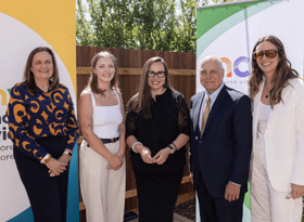 Group of 5 people standing outside in front of mcm and homes first banners