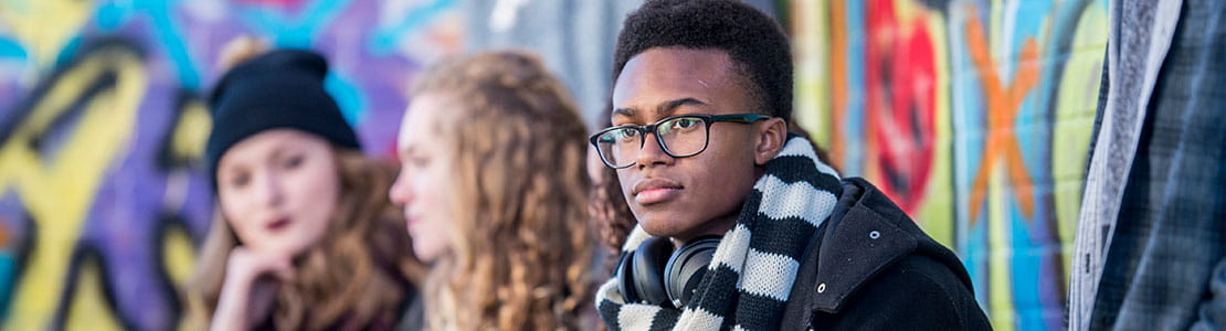 two teenage girls and a teenage boy wearing black and white scarf sit together