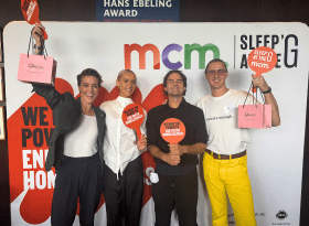 4 people standing in front of a sleep at the g wall holding cupcakes and signs