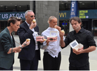 4 people standing outside the MCG eating cupcakes