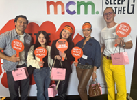 Group of people standing in front of MCM Sleep At The G wall holding sleep at the g paddles