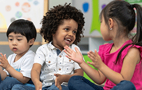 Three young children playing on the floor of a childcare setting