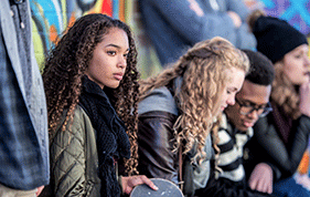 Teenage girl with long hair sitting with a group of other teenagers