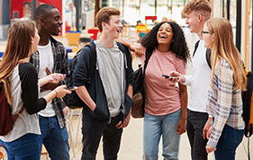 Group of six teenage students standing around each other and smiling