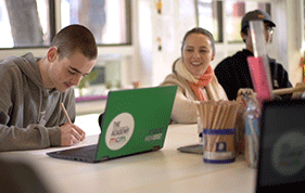 Hester Hornbrook Academy student working on his laptop beside a female youth worker