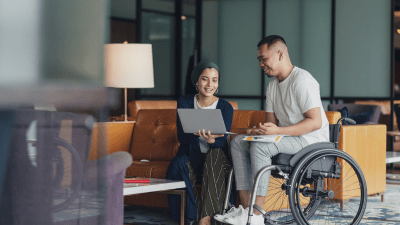 Man with disability in a wheelchair discussing work with a co worker