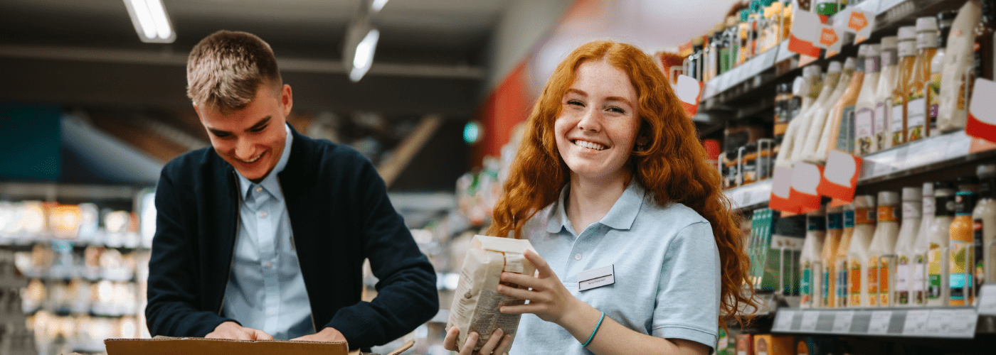 Shop assistants re-stocking fresh vegetables in produce aisle