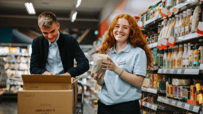 Shop assistants re-stocking fresh vegetables in produce aisle