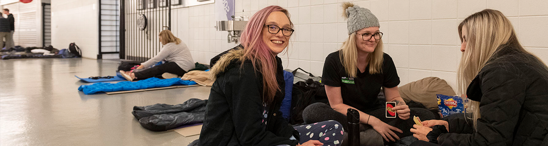 Group of three girls sitting on the floor playing cards smiling