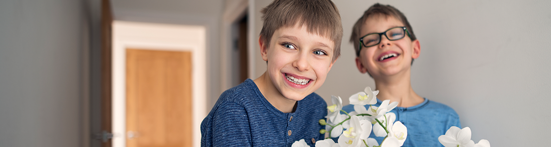Two young boys holding some flowers and smiling