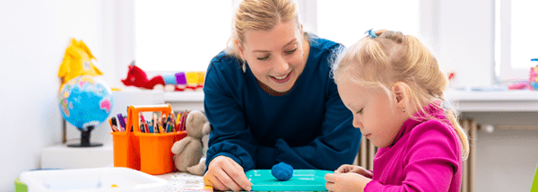 Photo of a woman key worker therapist and a young girl playing with playdoh