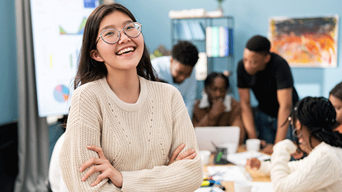 Female student wwearing glasses smiling on front of a group of people